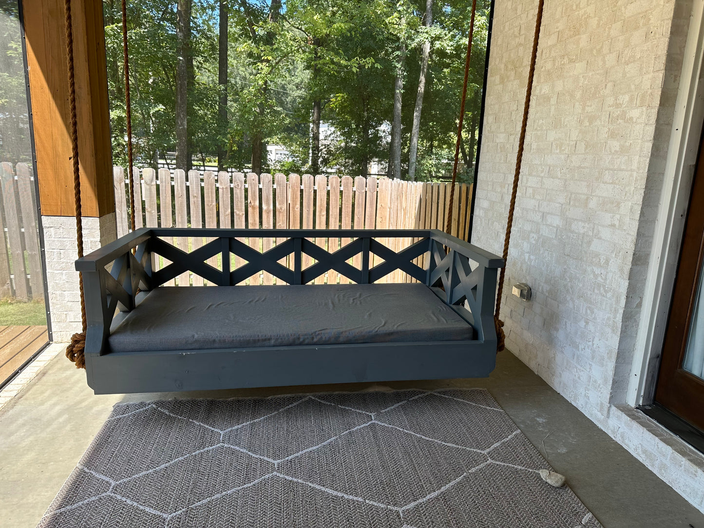Crisscross SwingBed showing the crisscross rail design in dark navy finish on a screened porch