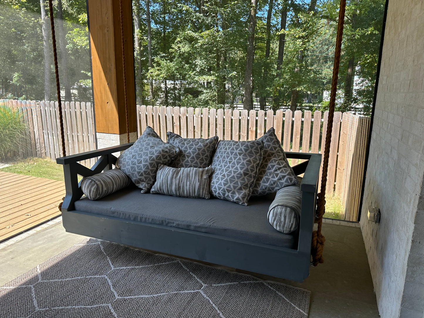 Crisscross SwingBed in dark navy finish with geometric print pillows on a screened porch